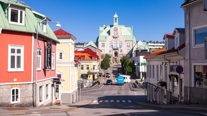 Strömstad centrum. Trähus i olika kulörer, rött, gult och beige. Längst bort i bild tornar en stor beige byggnad upp med torn och klocka på utsidan.