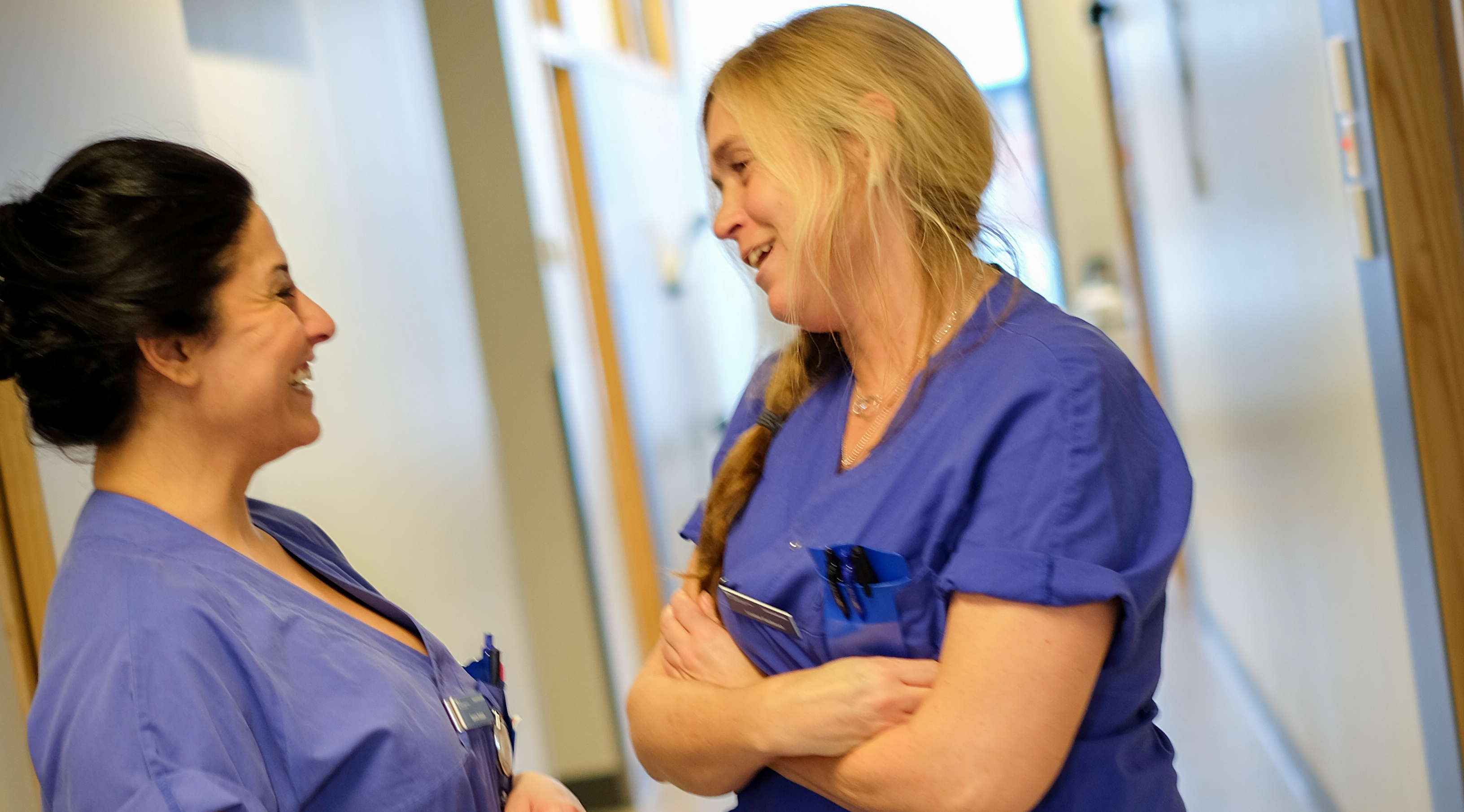 Två medarbetare ståri en korridor och pratar med varandra.