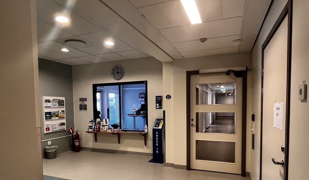 Reception med glasfönster, anslagstavla till vänster och klocka ovanför. 