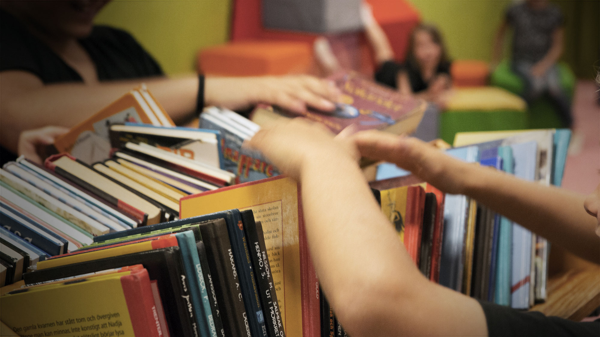 Barn som bläddrar bland massor av biblioteksböcker.
